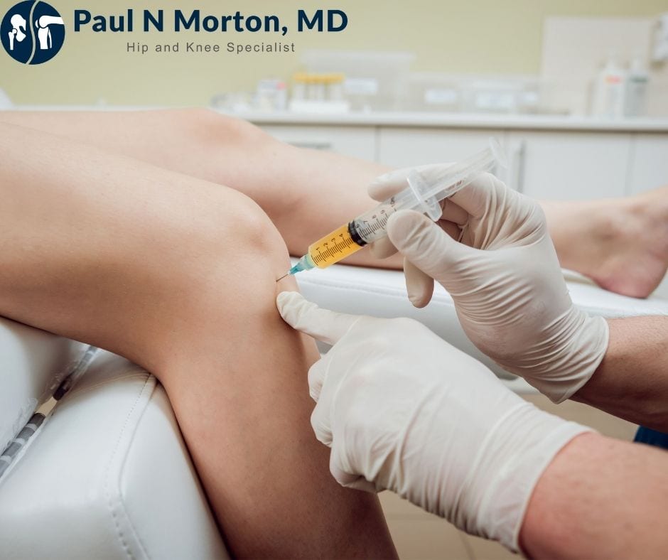A gloved clinician injects platelet-rich plasma into a patient's knee in a clinic exam room.