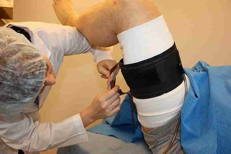 A clinician secures a padded thigh tourniquet cuff on a patient's leg before knee surgery — the step Dr. Morton's technique leaves out.
