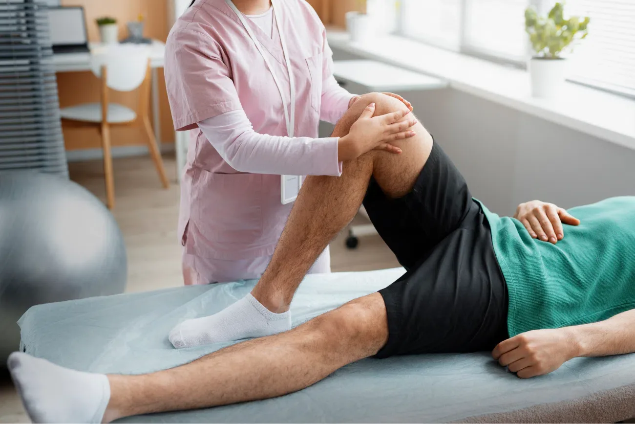 Physical therapist guiding a patient through knee flexion exercises on a treatment table.