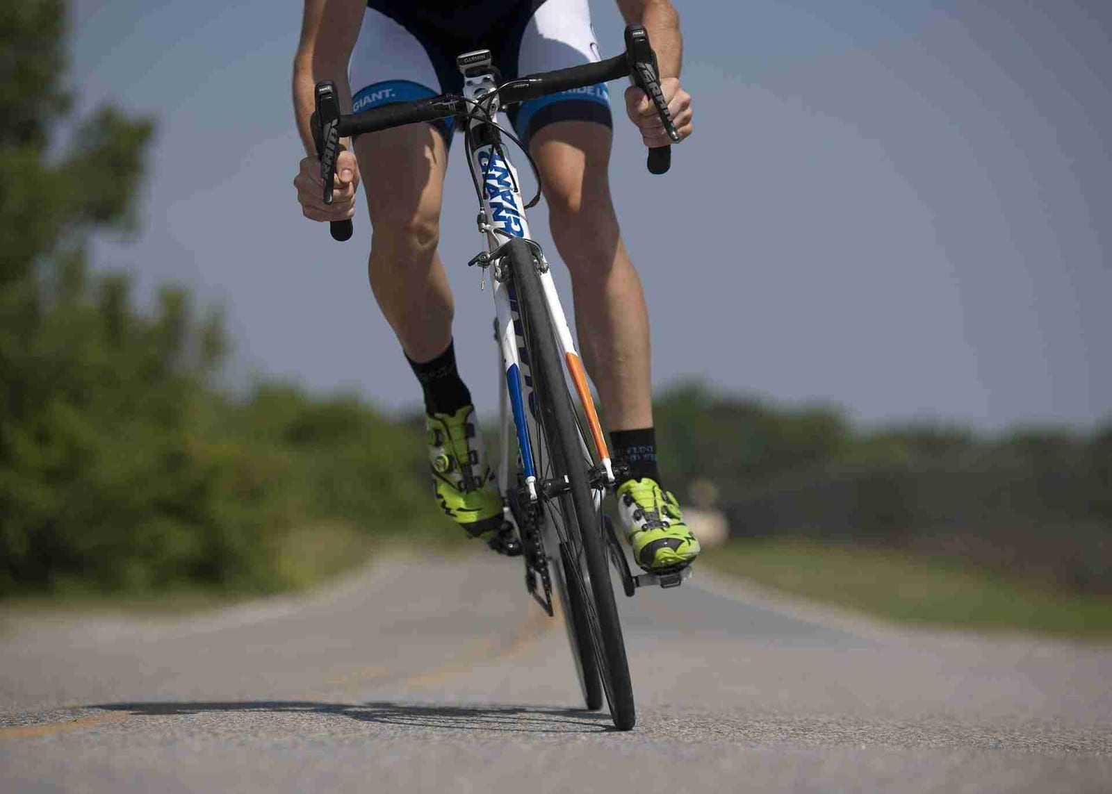Cyclist pedaling a road bike along a country road, an example of low-impact exercise for healthy joints.