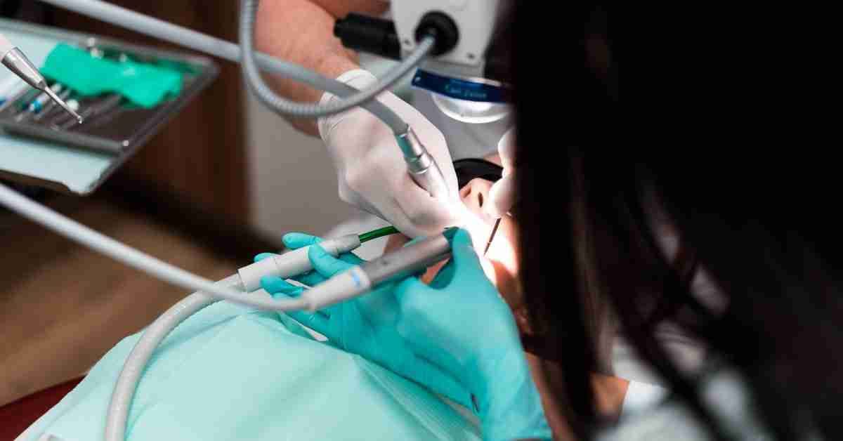 Dentist performing a procedure on a patient, illustrating dental care precautions after joint replacement surgery.