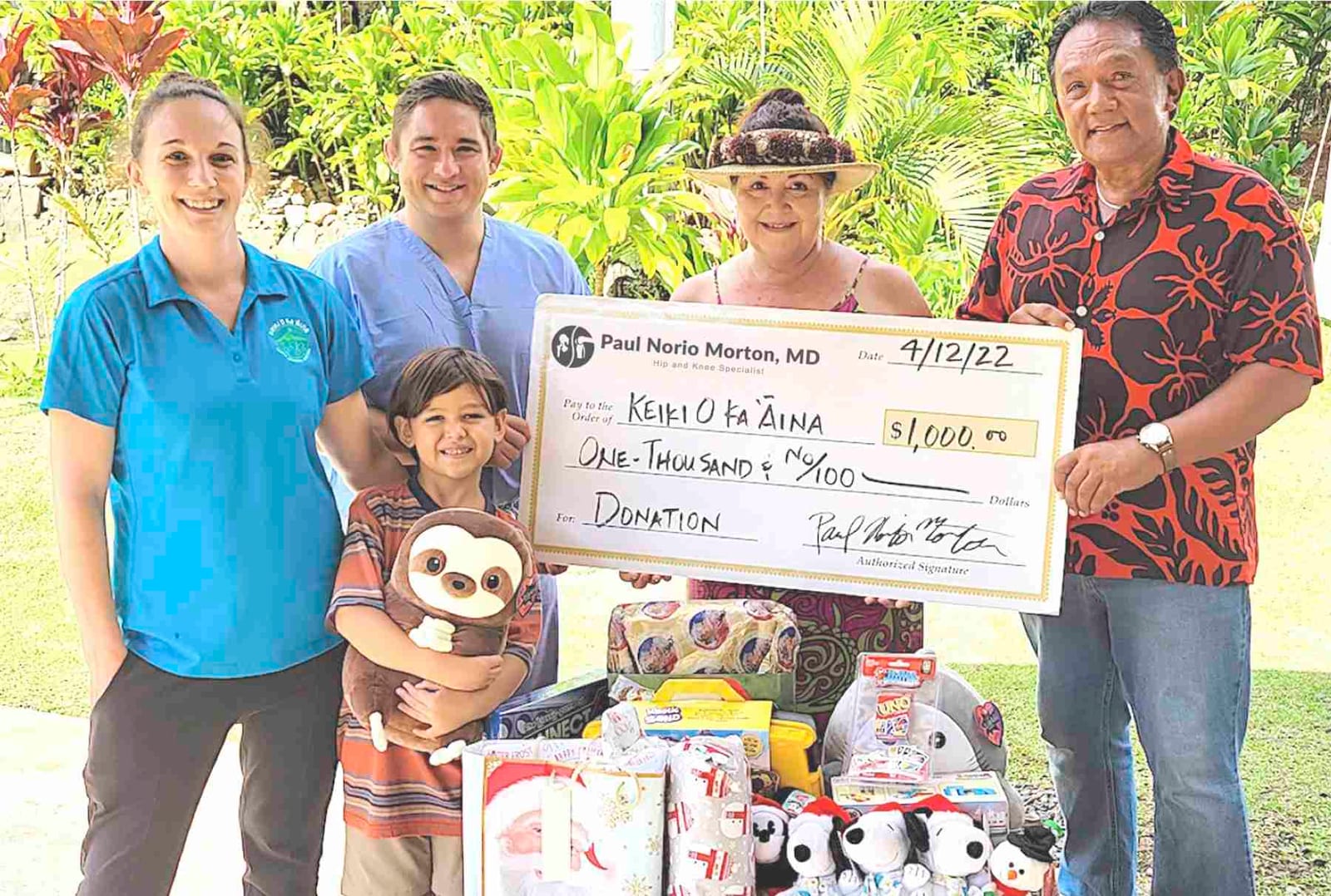 Dr. Paul Morton presenting a donation to the Keiki O Ka ‘Āina family learning center alongside staff and holiday toy gifts