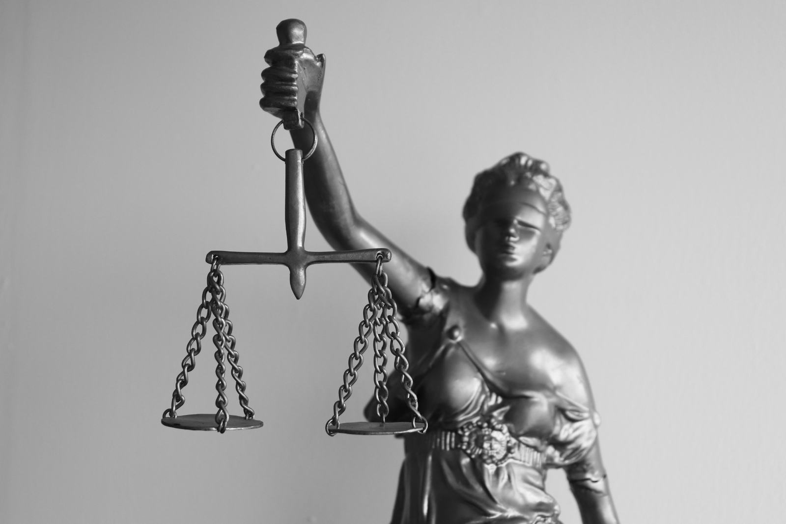 Black-and-white photo of a Lady Justice statue holding balanced scales.