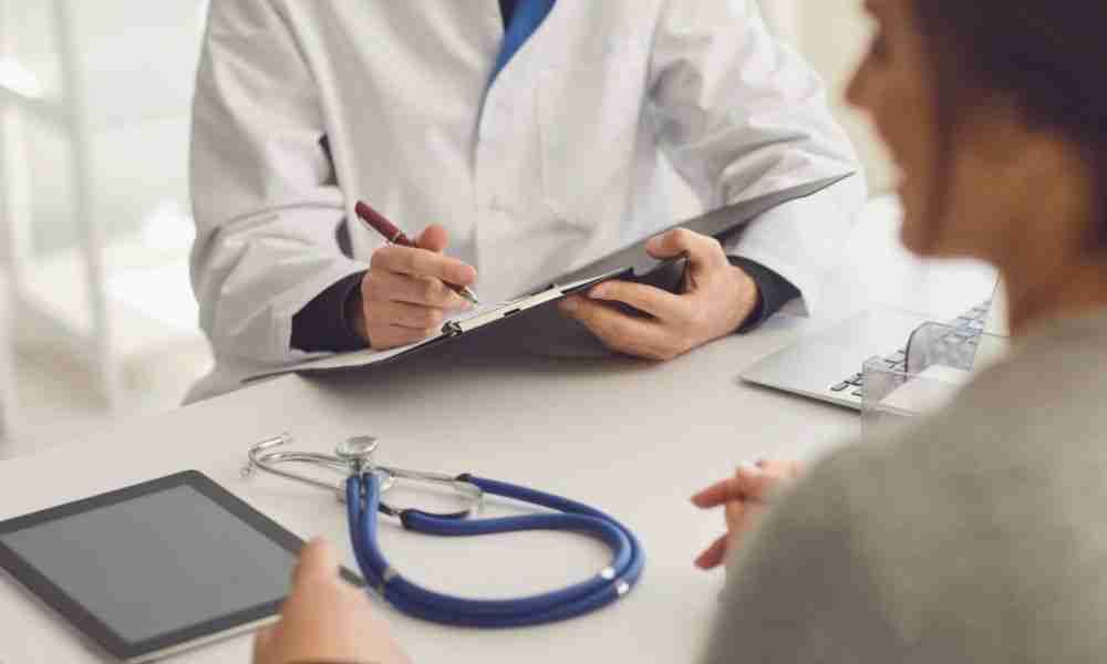 Doctor reviewing joint replacement paperwork with a patient during an office consultation.
