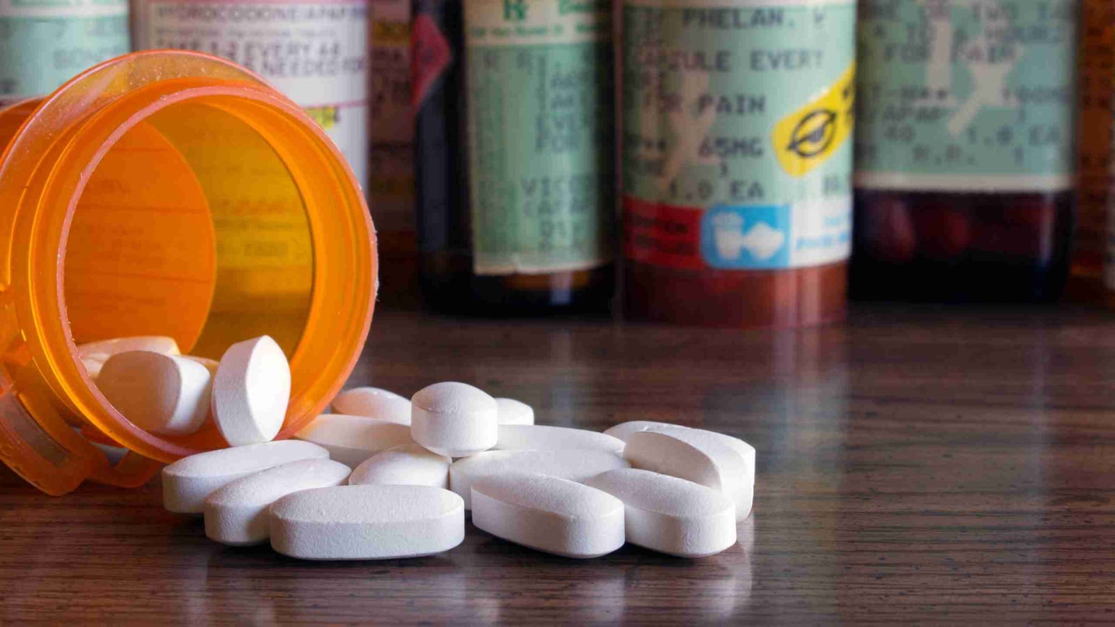 Prescription pain medication bottles with pills spilled onto a table — the opioids that modern multimodal surgery is designed to minimize.