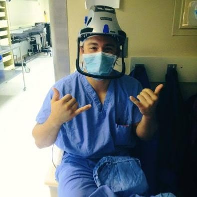 Dr. Paul Morton in surgical gear throwing double shaka signs in the operating room.