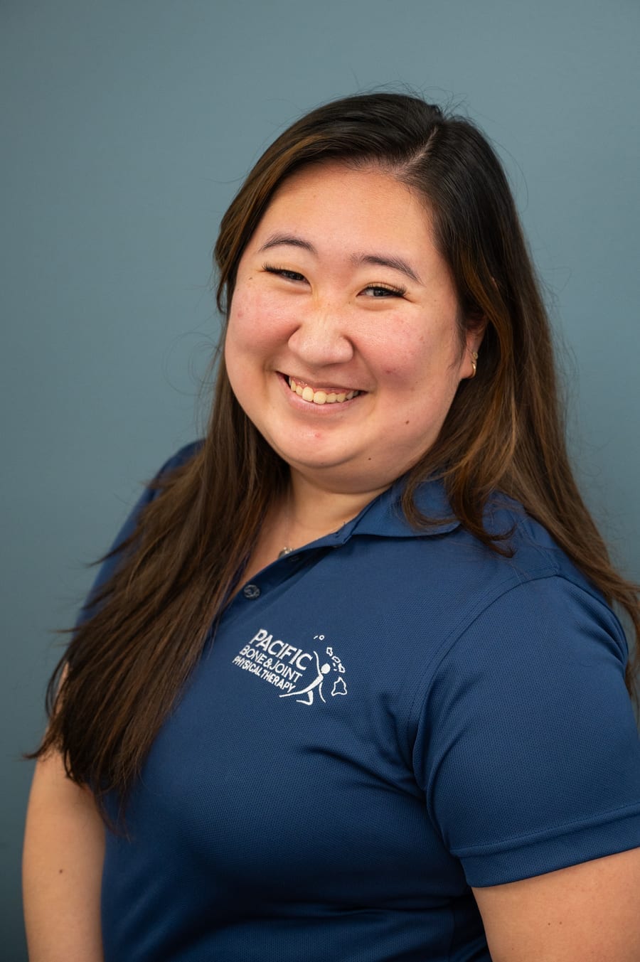 Kelcie, a PB&J Physical Therapy team member, smiling in a navy Pacific Bone & Joint polo.